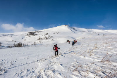 People walking on snow against sky