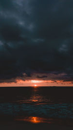 Scenic view of sea against cloudy sky during sunset