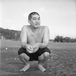 Portrait of shirtless man sitting on land