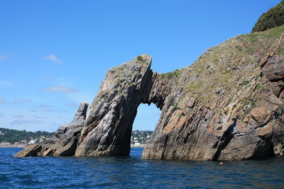 Rock formations by sea against blue sky