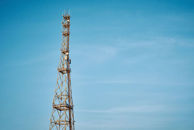 Communication tower with antenna against blue sky