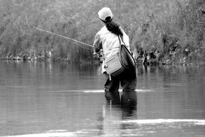 Rear view of woman fishing in river