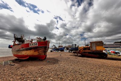 Boats moored in sea against cloudy sky