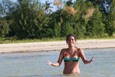 Smiling woman juggling plants in sea