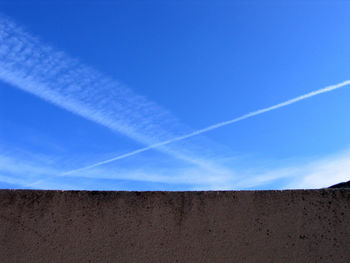 Low angle view of vapor trail against clear blue sky