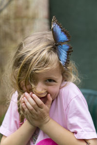 Portrait of smiling girl with butterfly in hair outdoors