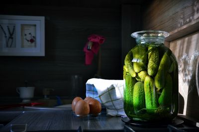 Close-up of cucumber pickle in jar by eggs on table at home