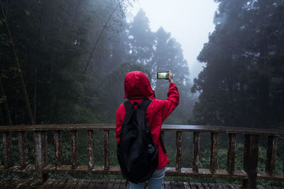 Rear view of man standing by railing during rainy season