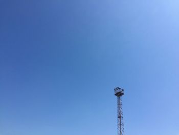 Low angle view of communications tower against clear blue sky