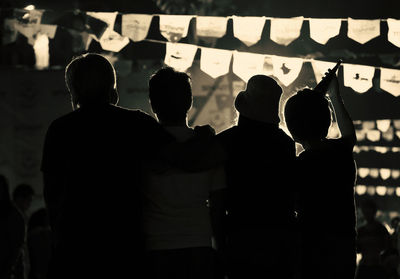 Silhouette friends on illuminated street at event