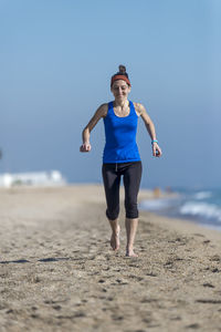 Full length of woman exercising on beach
