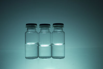 Close-up of empty glass bottle against blue background