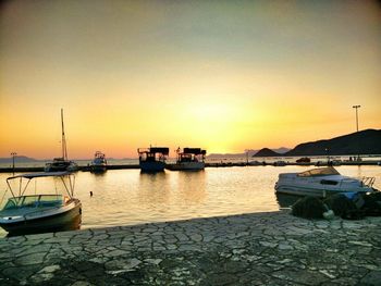 Boats moored at harbor against clear sky during sunset