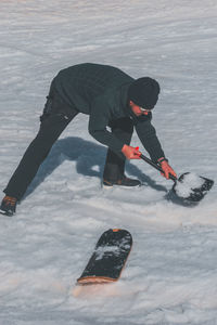 A caucasian man shoveling snow at a ski resort