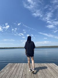 Rear view of woman standing on beach against sky