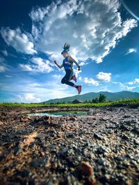 Low angle view of man jumping against sky