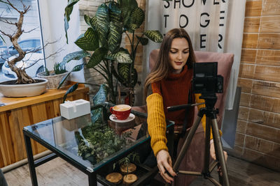 Content creator, blogger, vlogger setting up recording equipment and shooting video in cafe 