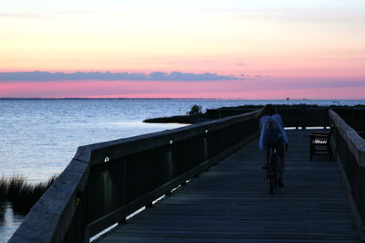 Rear view of man on pier over sea against sky