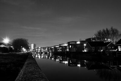 Canal by illuminated city against sky at night