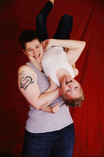 Portrait of playful mother and son against red fabric