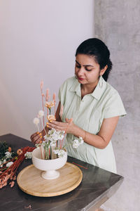 Side view of young woman making arragements on a ikebana center piece 