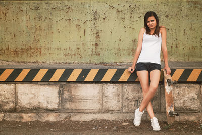 Portrait of young woman standing against wall