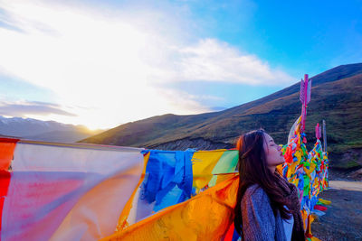 Woman leaning against multi colored flags on mountain