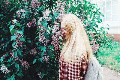 Side view of smiling young woman smelling flowers on tree