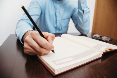 Midsection of man reading book on table