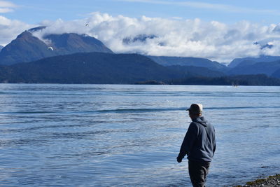 Rear view of man looking at sea against mountains