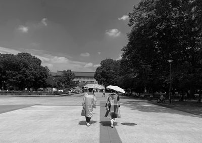 Rear view of people walking on road against sky