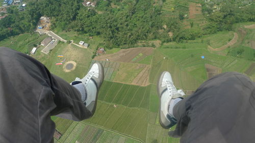 Low section of man paragliding over landscape