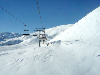 Overhead cable car in snow covered mountains against sky