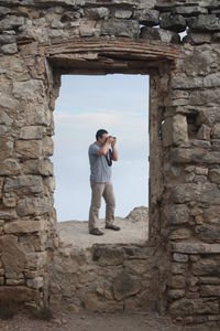 Full length of man photographing against sky