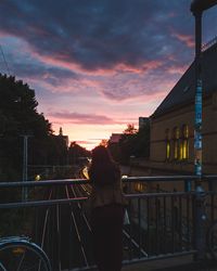 Rear view of silhouette woman standing by railing against sky