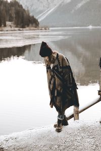 Woman standing by lake against sky during winter