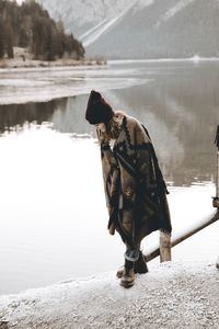 Close-up of young woman standing on rock by lake during winter