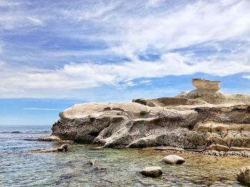 Rock formations by sea against sky