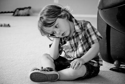 Little boy holding mobile phone to ear while sitting on floor