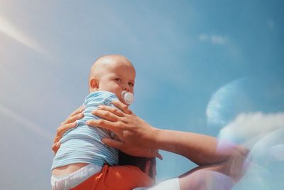 Low angle view of cute baby against sky