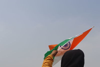 Low section of person holding paper against clear sky