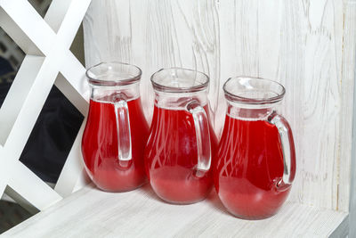 Three decanters with red berry juice on the sideboard. horizontal photo