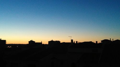 Silhouette cityscape against clear sky