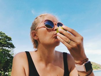 Portrait of woman holding ice cream against sky