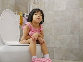 Girl looking away while sitting in bathroom