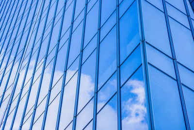 Low angle view of glass building against blue sky