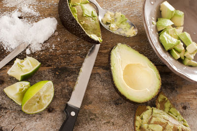 High angle view of knife and halved avocado on wooden table