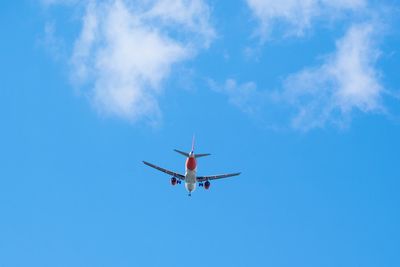 Low angle view of airplane flying against blue sky