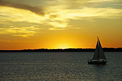 Sailboat sailing on sea against sky during sunset