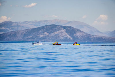 Boats in lake against mountain range